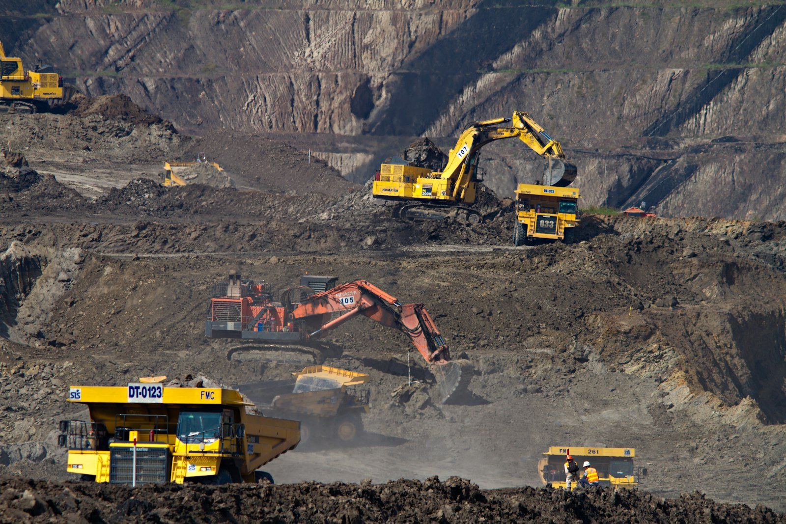 Excavators loading haul trucks on terraced benches at a coal mine; illustrative mining operations.