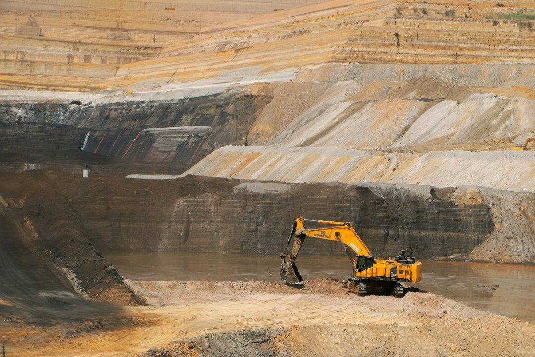Yellow excavator working in a large open-pit mine